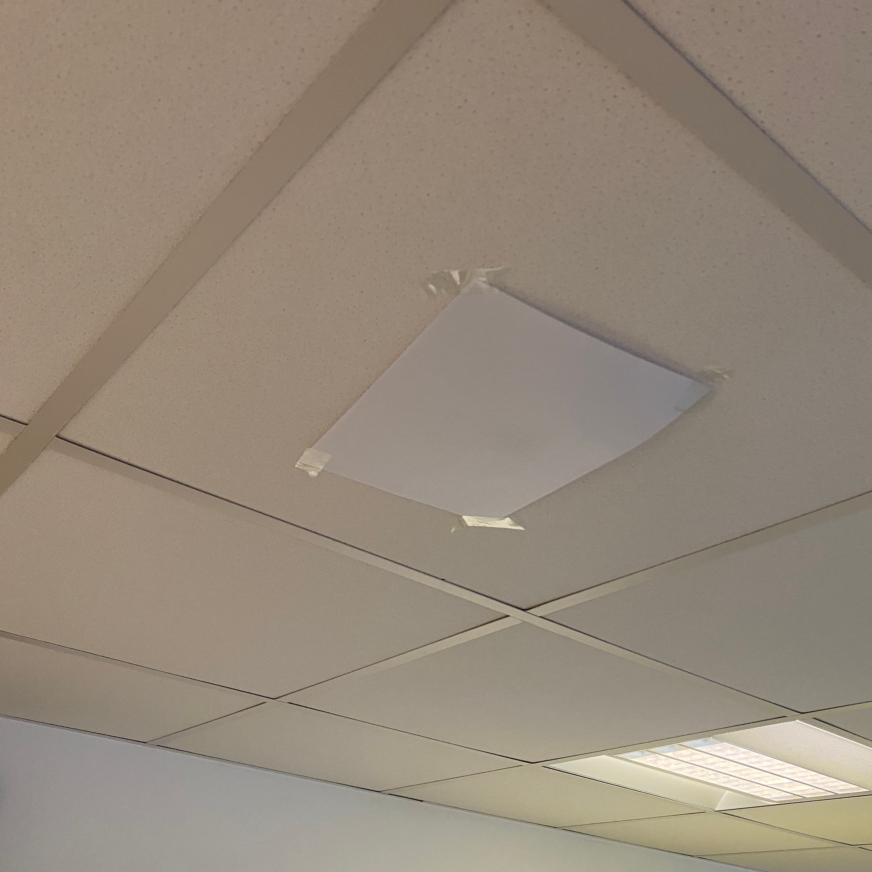 Sheet of paper taped to an office ceiling over a movement sensor.